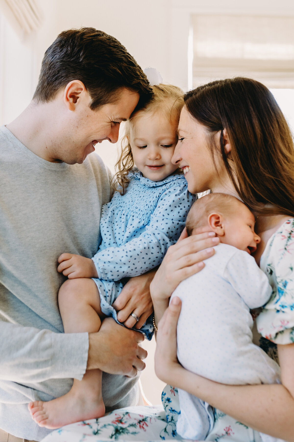 family og four hugging holding newborn