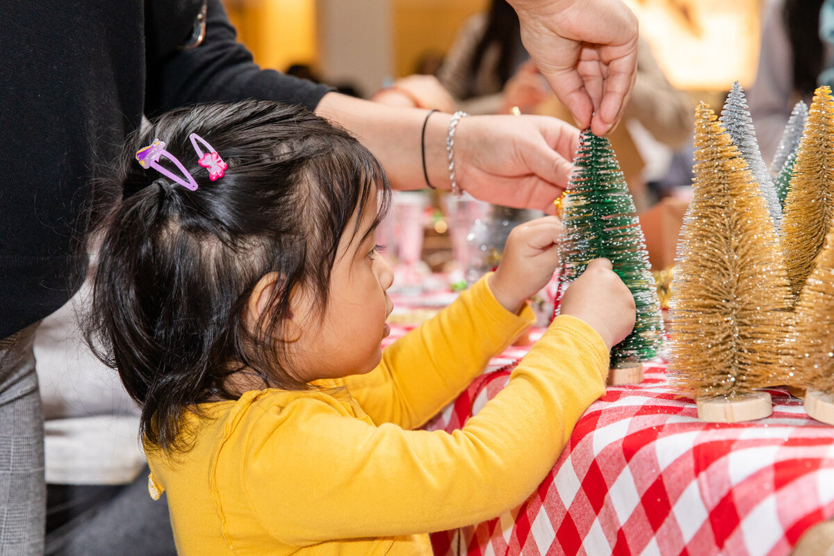 toddler decorating a Christmas tree during a company holiday event in Atlanta by Laure Photography