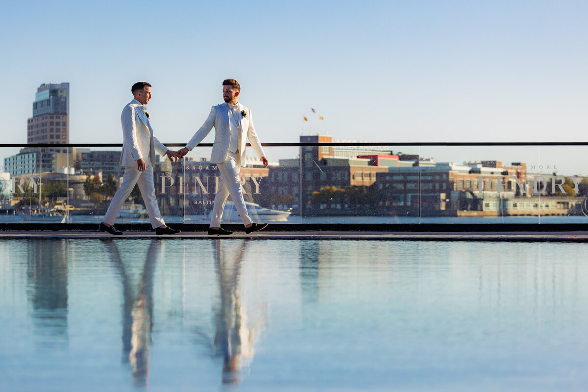 Two people holding hands and walking along the edge of a pool overlooking Baltimore city