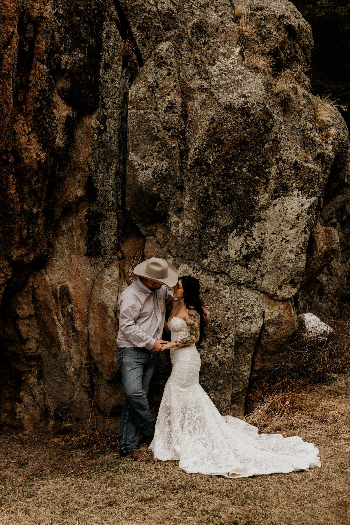 bride and groom standing against a rock in New Mexico