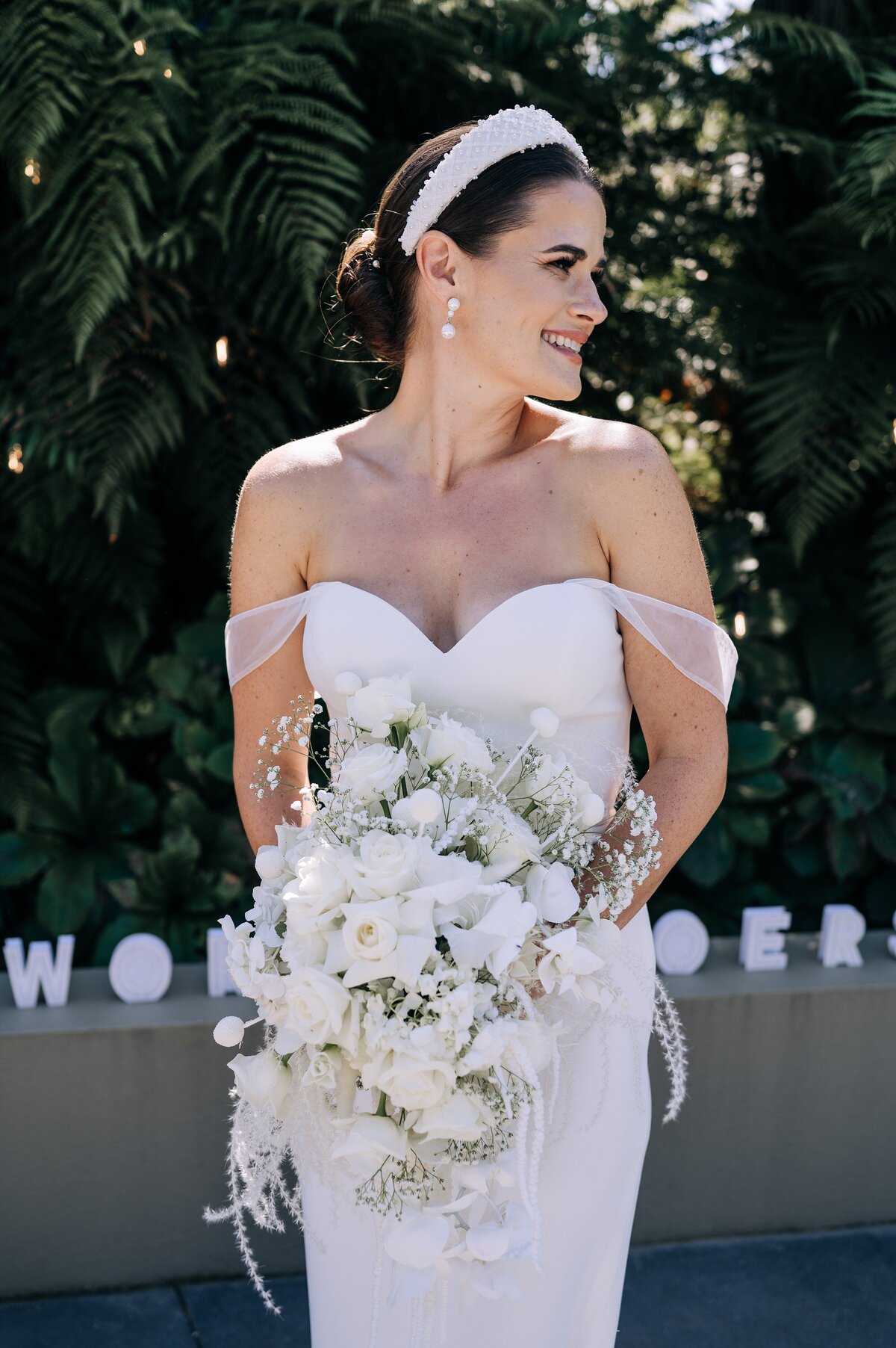 bride in trish peng gown with white bouquet and white beaded headband