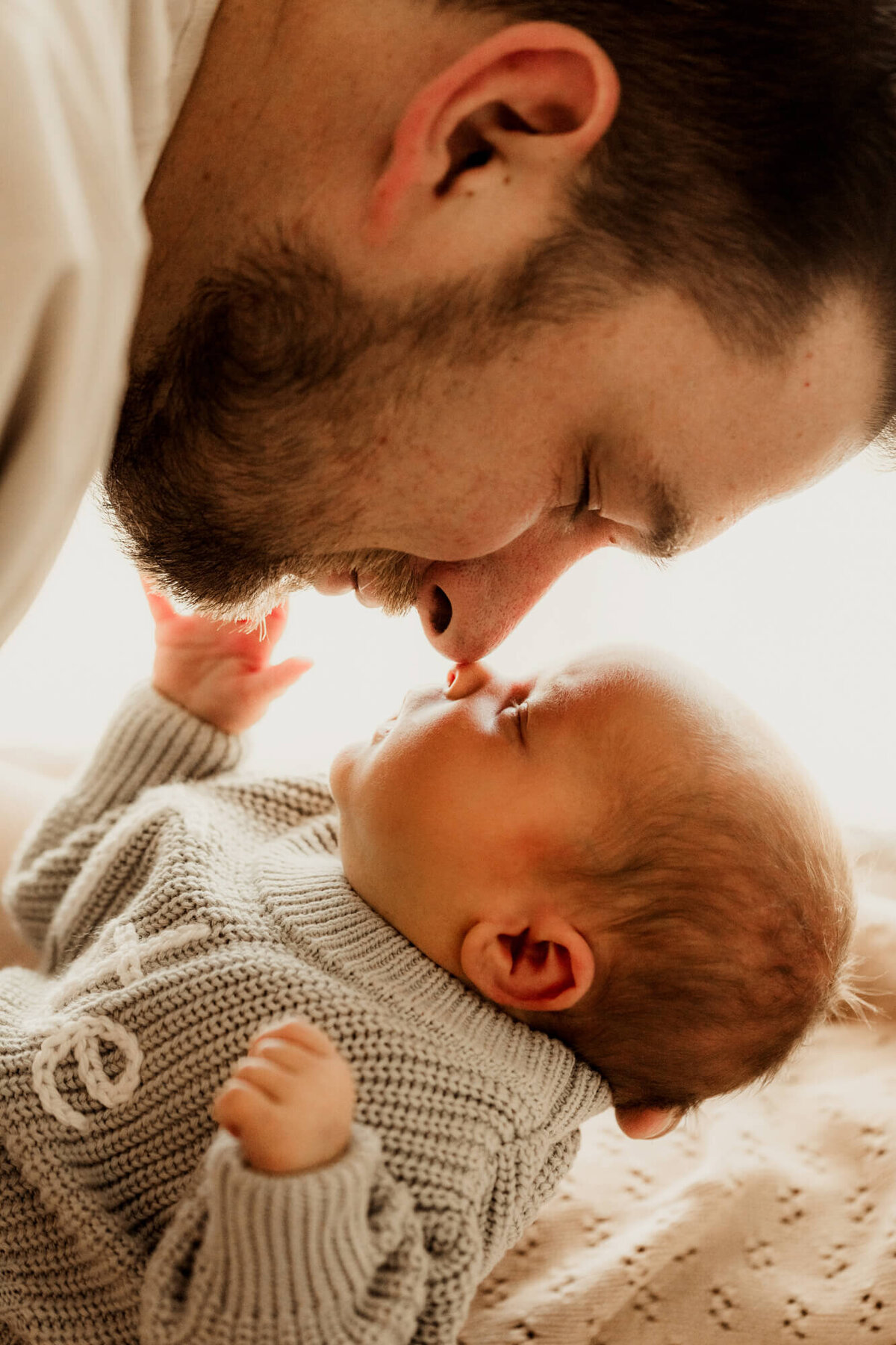 Father and son touching noses with the baby boy's hand up next to his father's face.