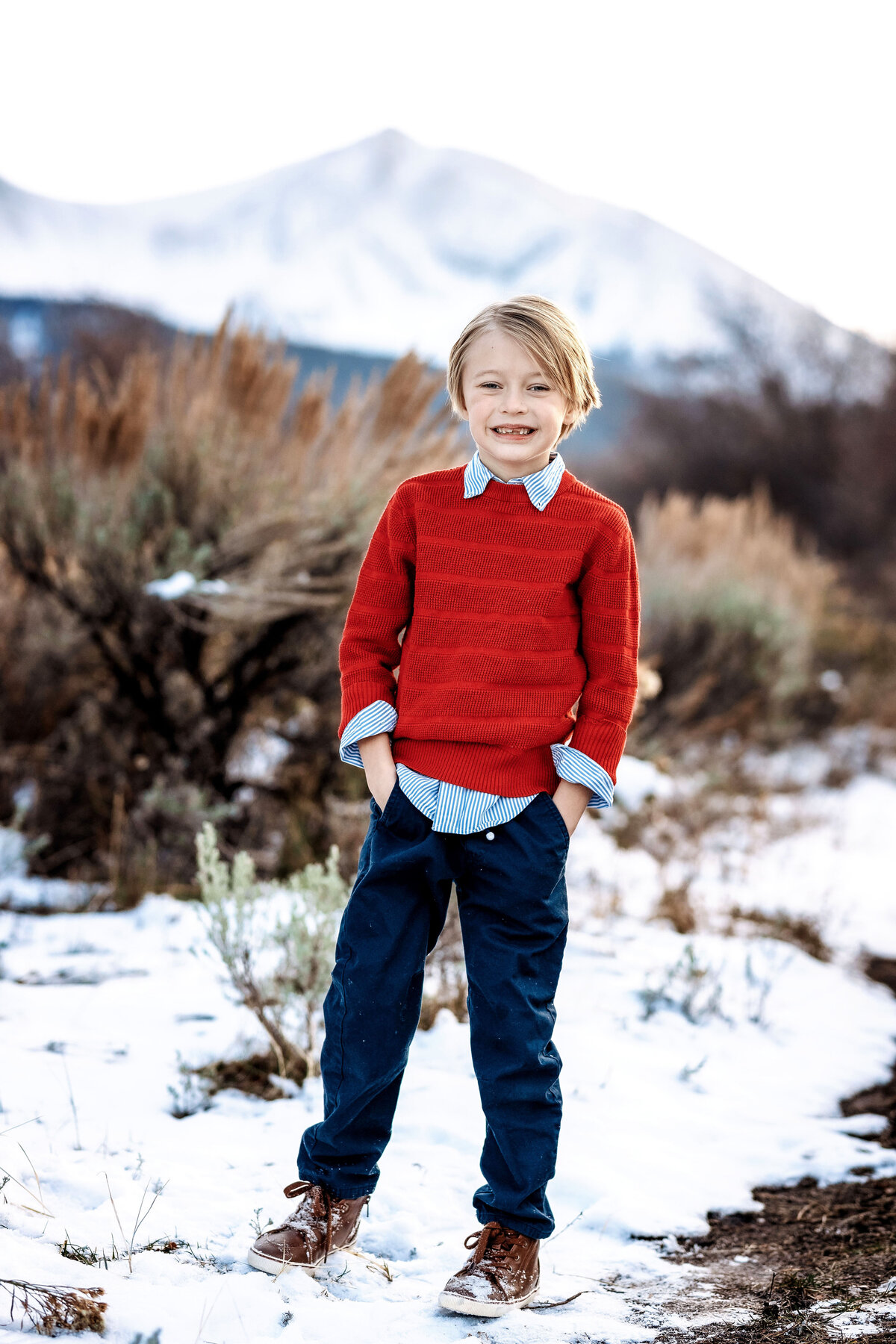 A happy little boy wearing a bright red sweater, smiling for the camera.