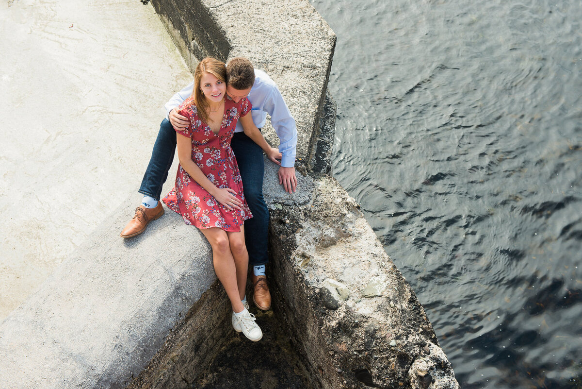 engagement portrait of male and female couple sitting by the water