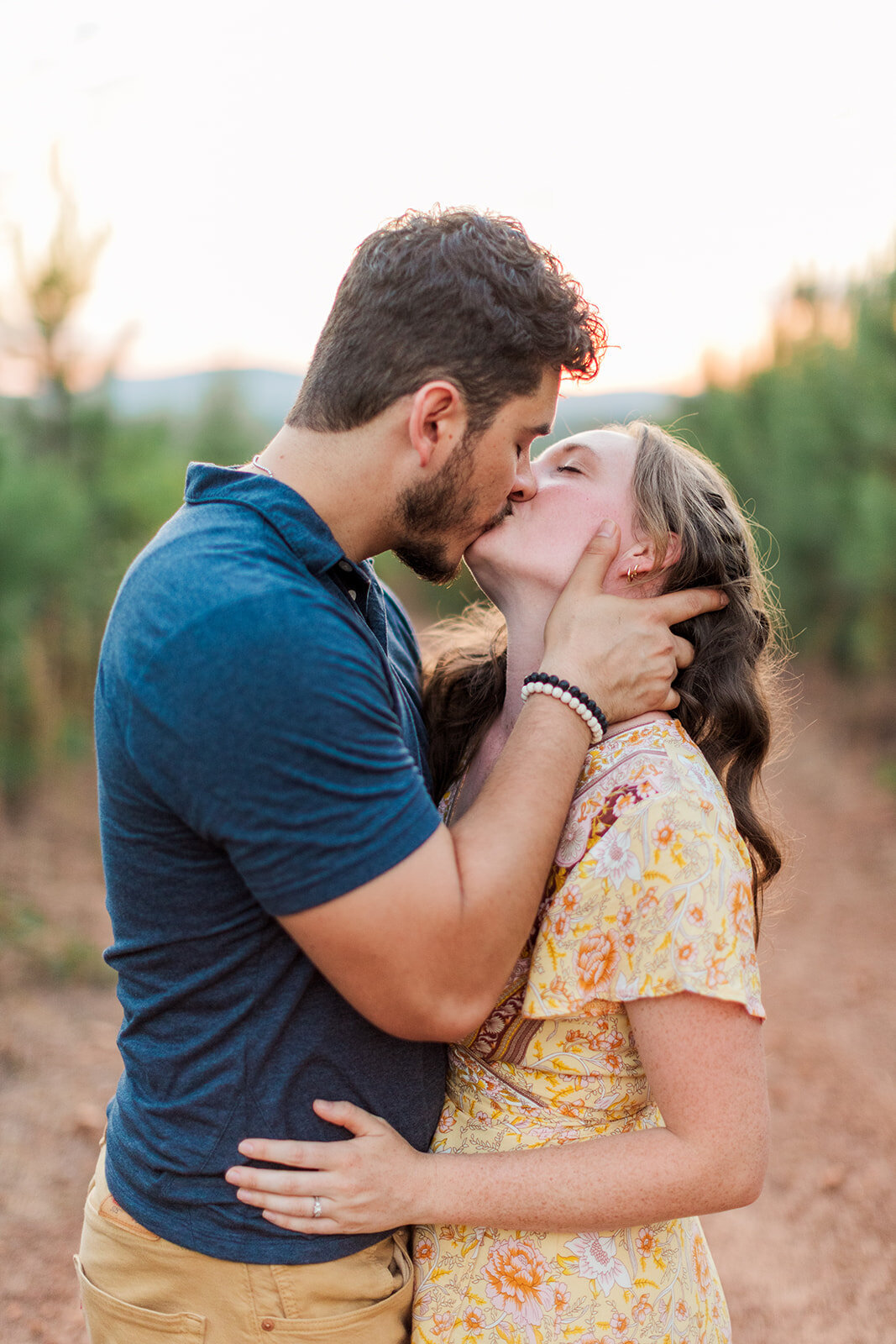 Mom and dad kissing with baby at sunset