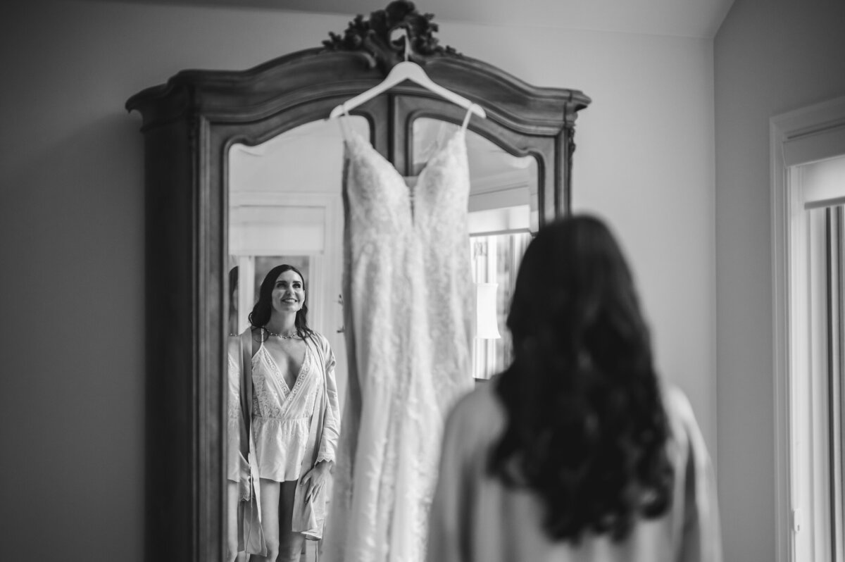 Bride looks at her wedding dress in a mirror