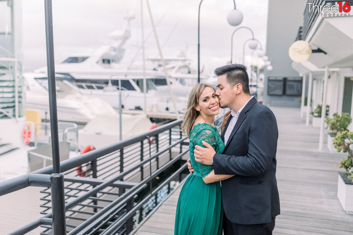 Bride to be accepts a kiss from her Groom  while posing at Lido Marina Village