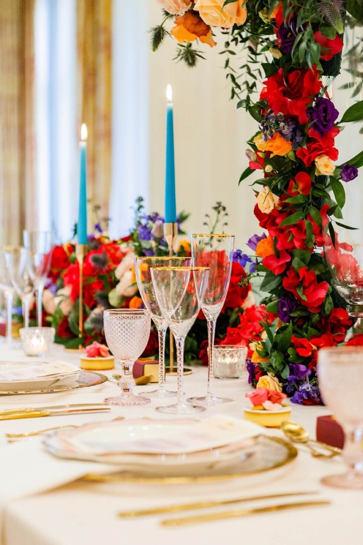 Fine dinning with luxurious table setting with gold rimmed glasses. Tropical florals with baby blue candles