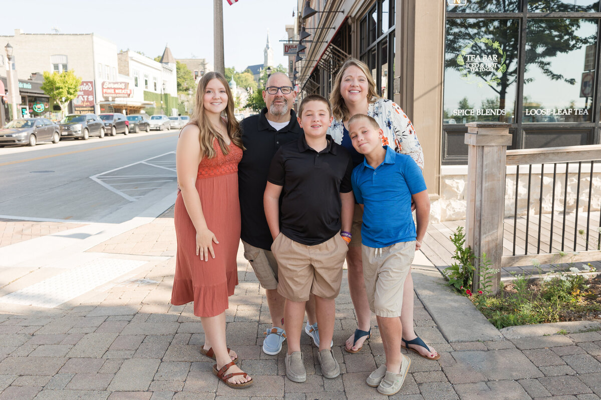 A family is standing on a street corner together and smiling at the camera