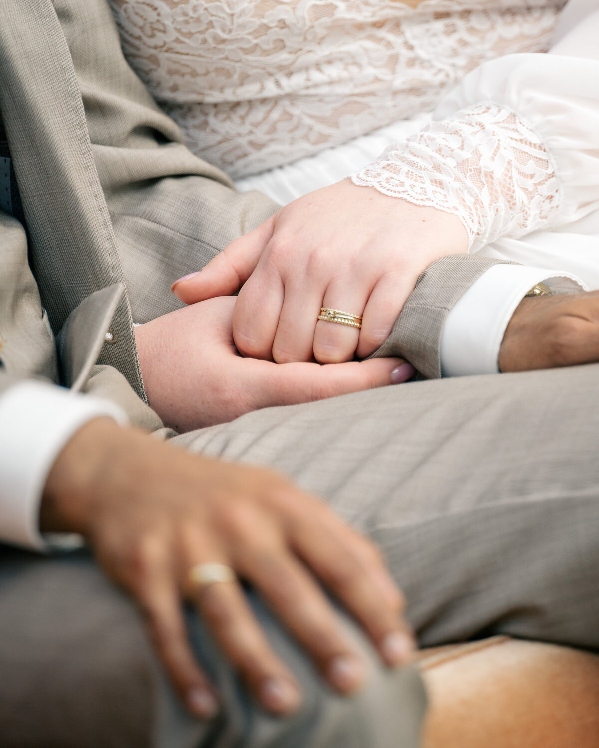 Detail of a bride holding the arm of the groom fast during the ceremony with rings in view