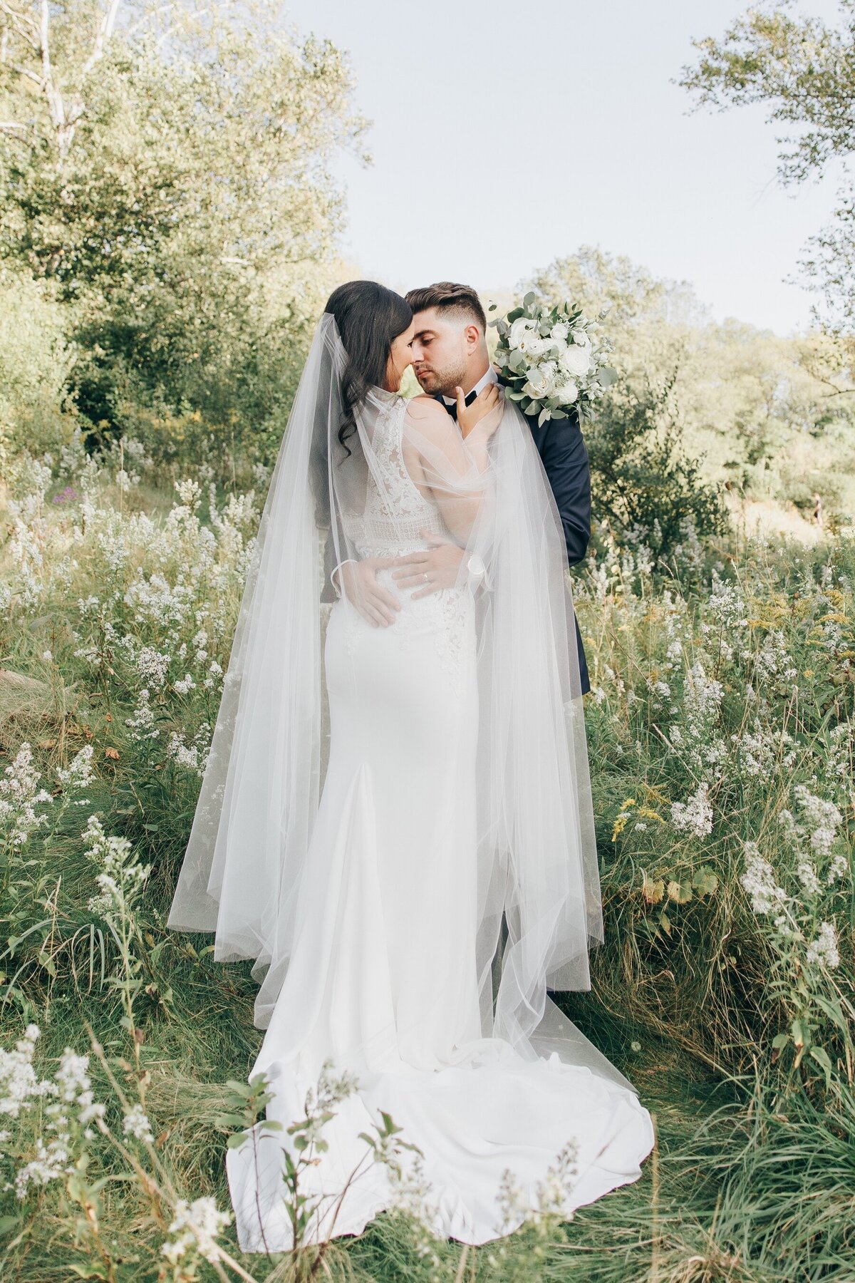 A bride and groom kissing in a field