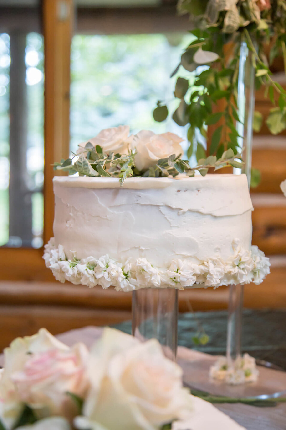 a one tier wedding cake with pink roses in a cabin