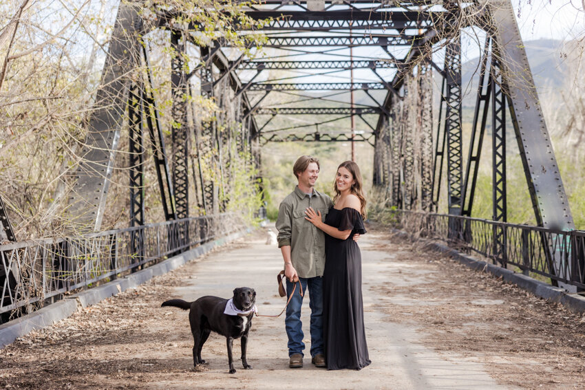engaged-couple-walking-with-dog-on-Sweetwater-River-Bridge