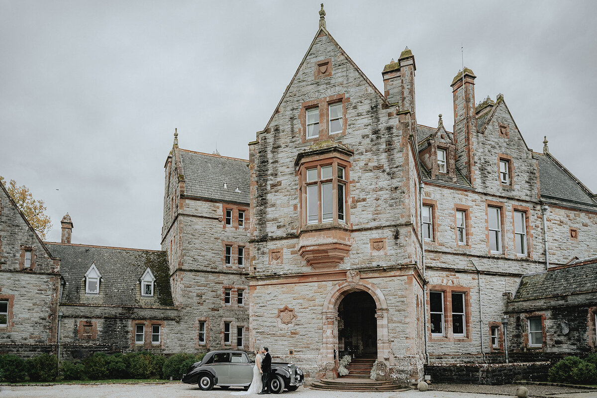 Bride and groom hugging in front of retro car in Ireland