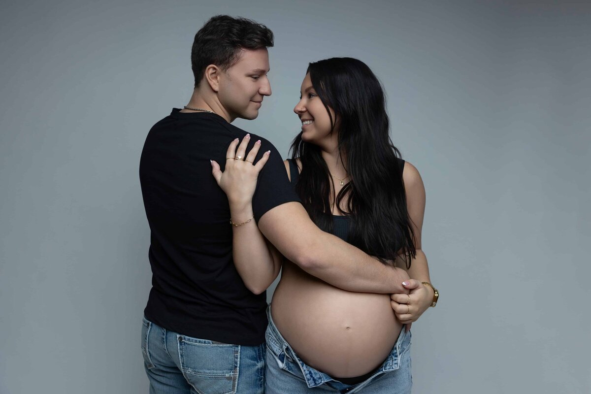 pregnant mom and dad embracing and laughing at eachother