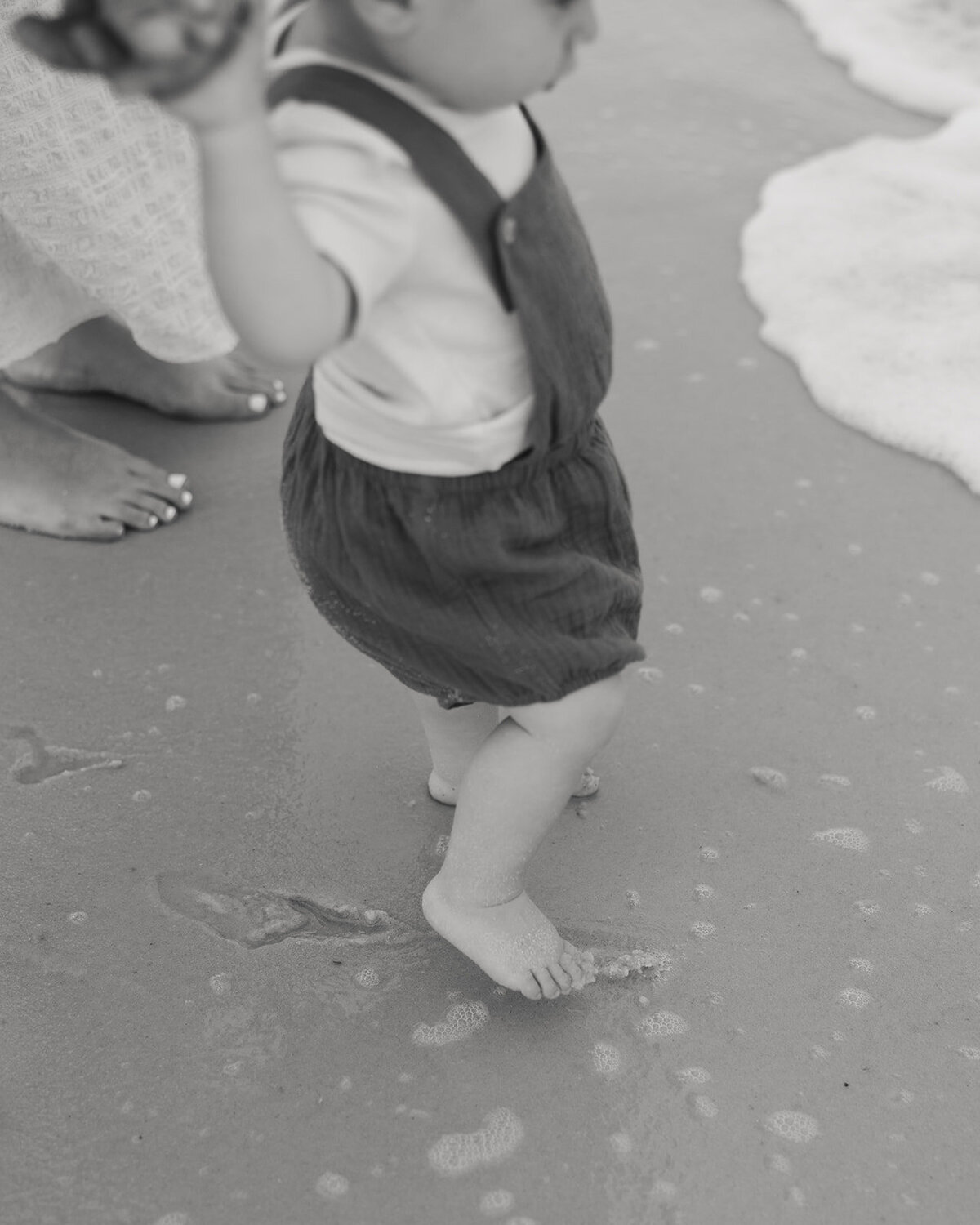 little boy plays by the ocean