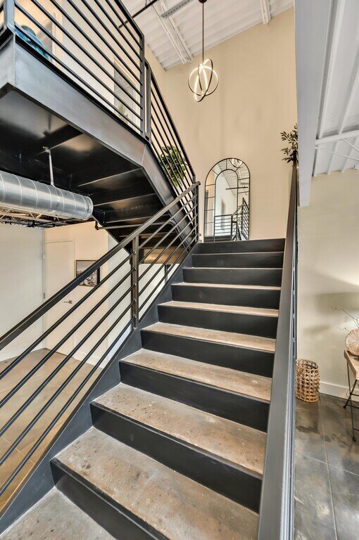 Stairs connecting main floor and upstairs bedrooms in this 2 bedroom, 2.5 bathroom luxury vacation rental loft condo for 8 guests with incredible downtown views, free parking, free wifi and professional decor in downtown Waco, TX.