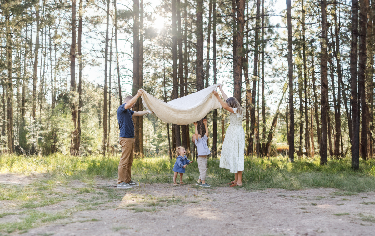 mom and dad and kids playing a game with a blanket