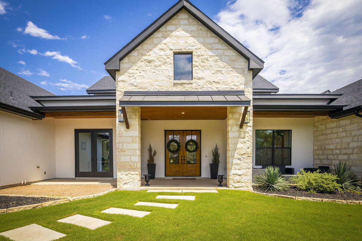 limestone and white stucco house with wood double front doors