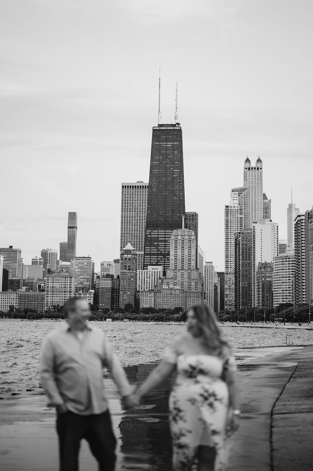 A couple hold hands with the Chicago skyline in the background at North Avenue Beach
