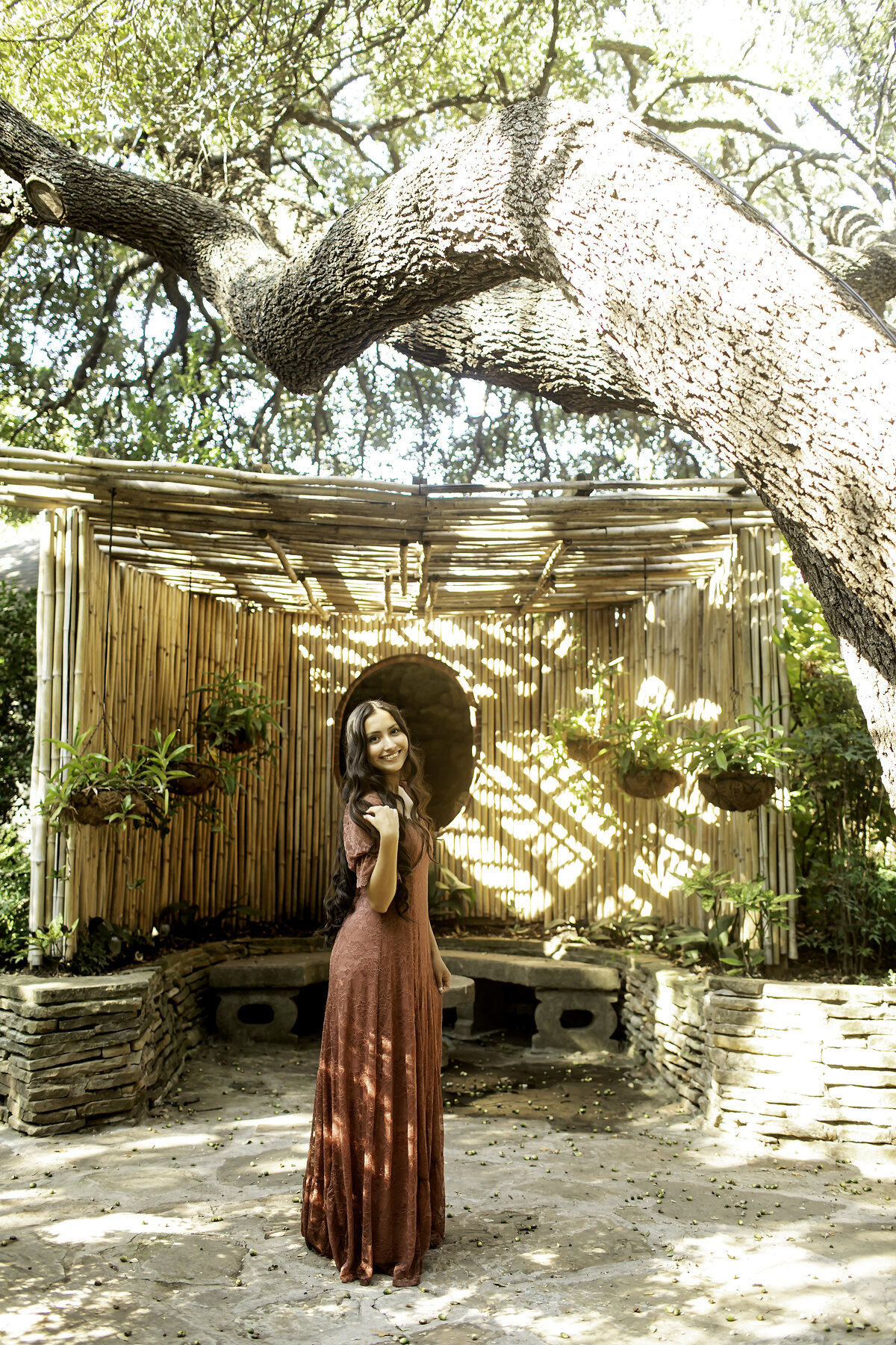 A high school senior posing near the stone pathways of Chandor Gardens, Weatherford, TX, with the vibrant blooms creating a picturesque and peaceful setting