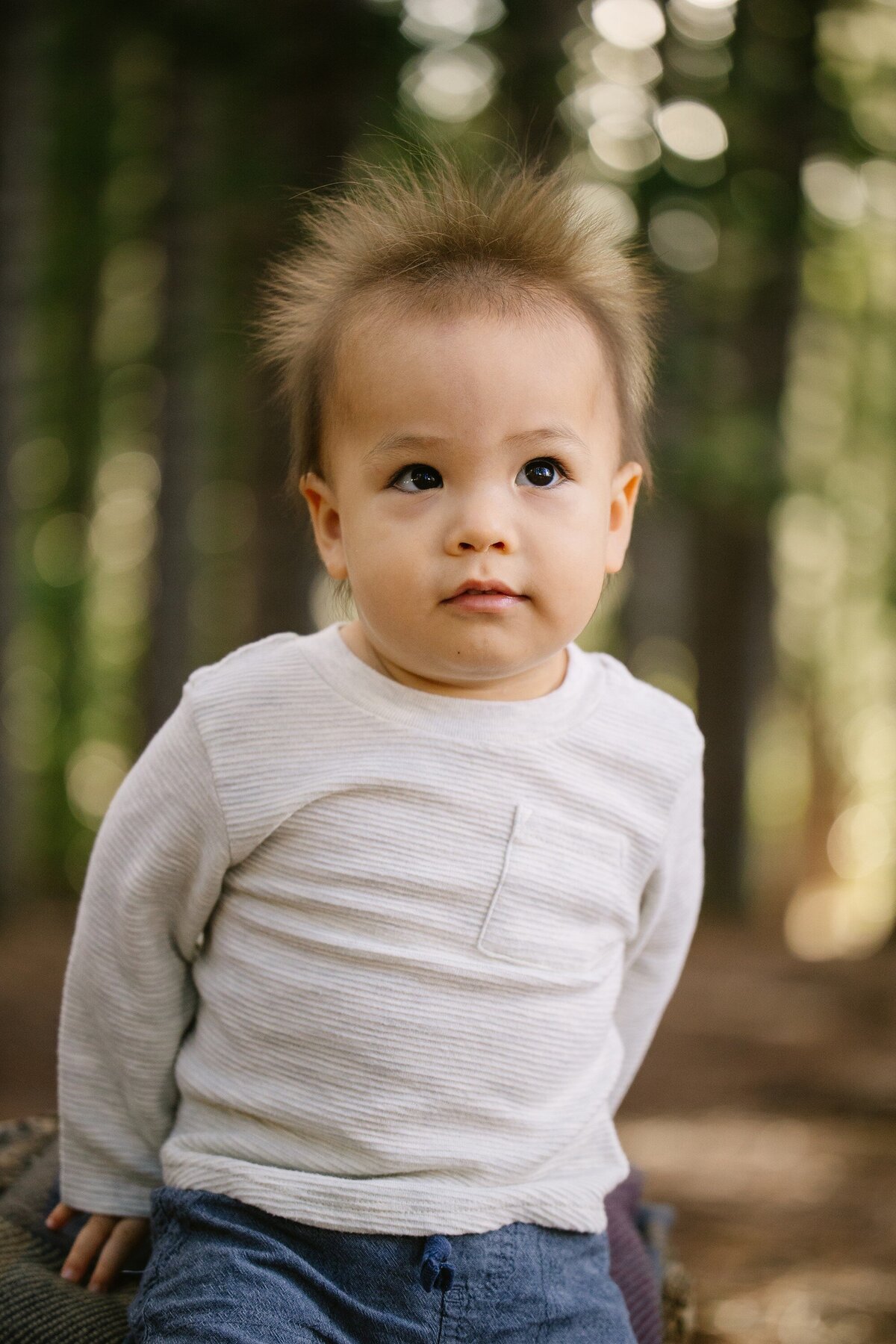 toddler with fuzzy hair poses on a log