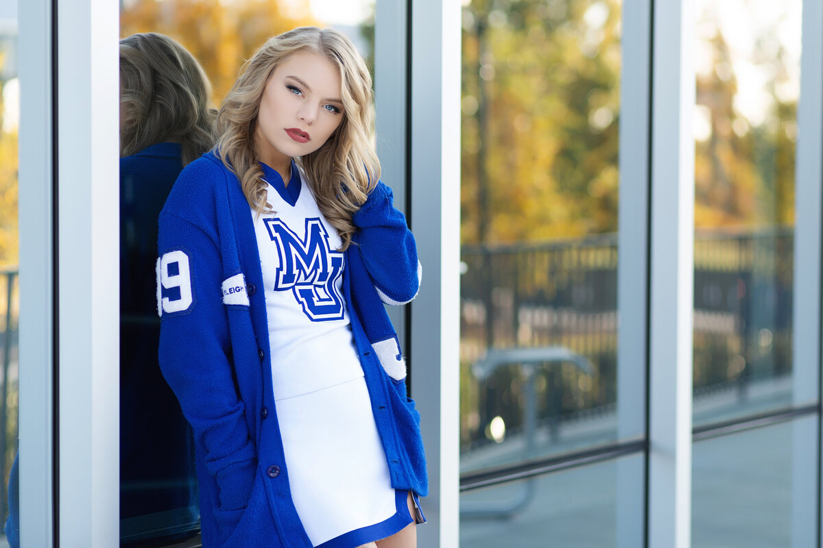 Senior cheerleader posing in front of a glass wall.