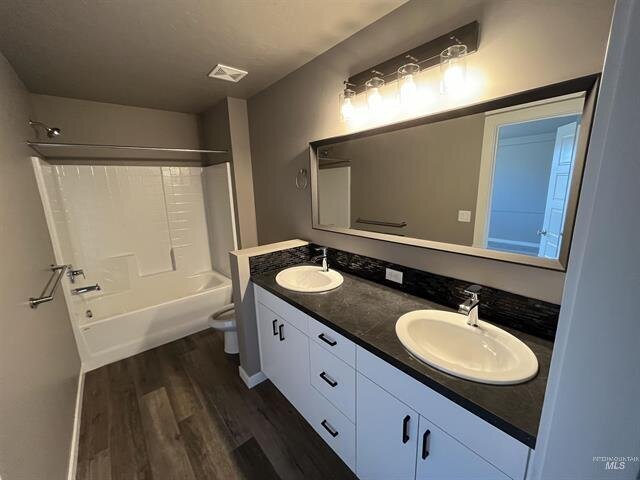 bathroom with jack and jill sinks with white vanity cabinets and wood floors