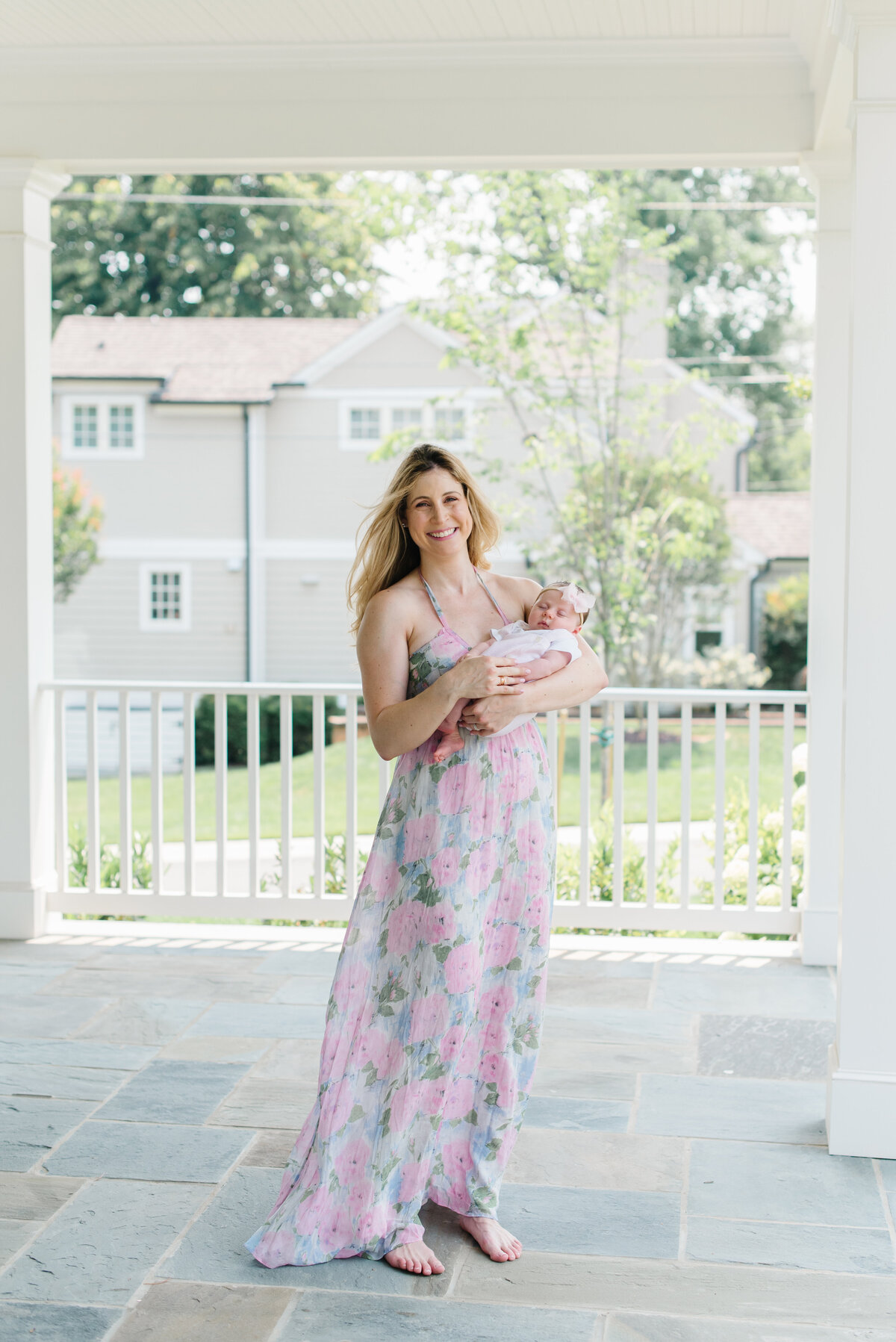 Mother holding baby outside on a porch smiling