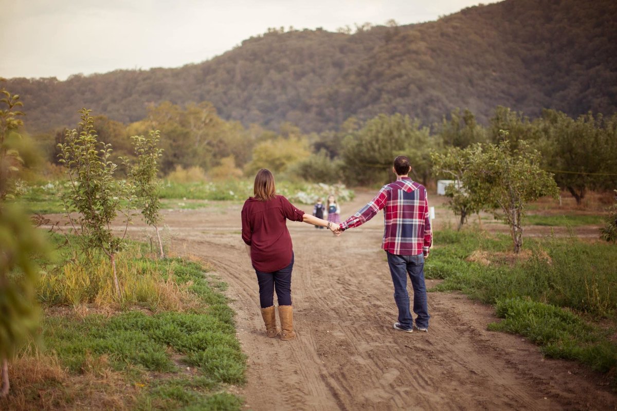 Husband and Wife walk along a trail holding hands with their outstretched arms