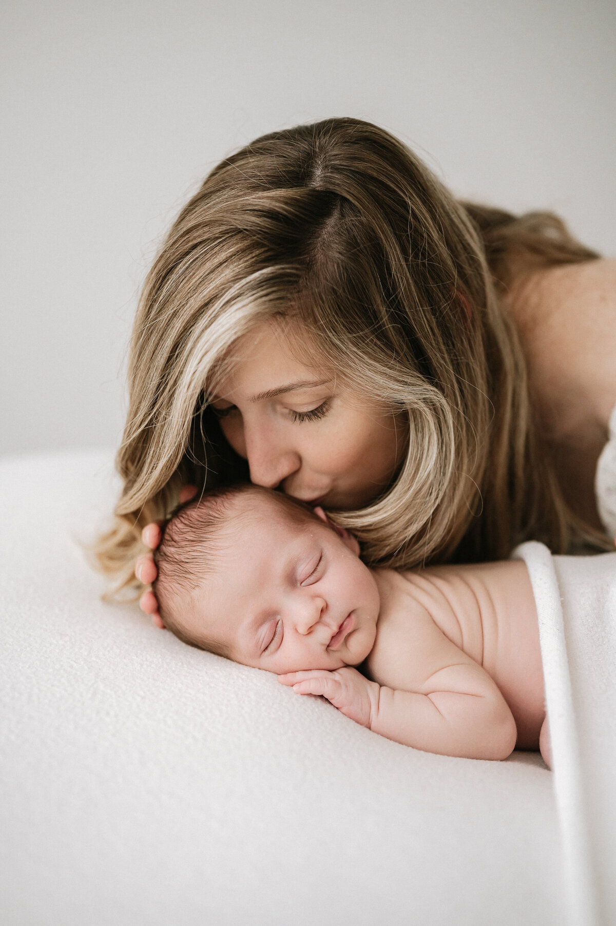 Mother kissing her little newborn baby