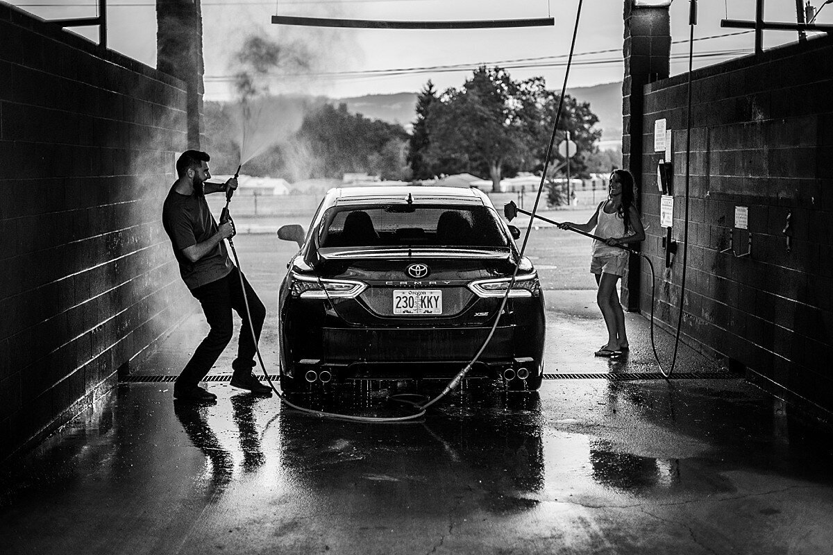 Fun couple spraying water at the car wash