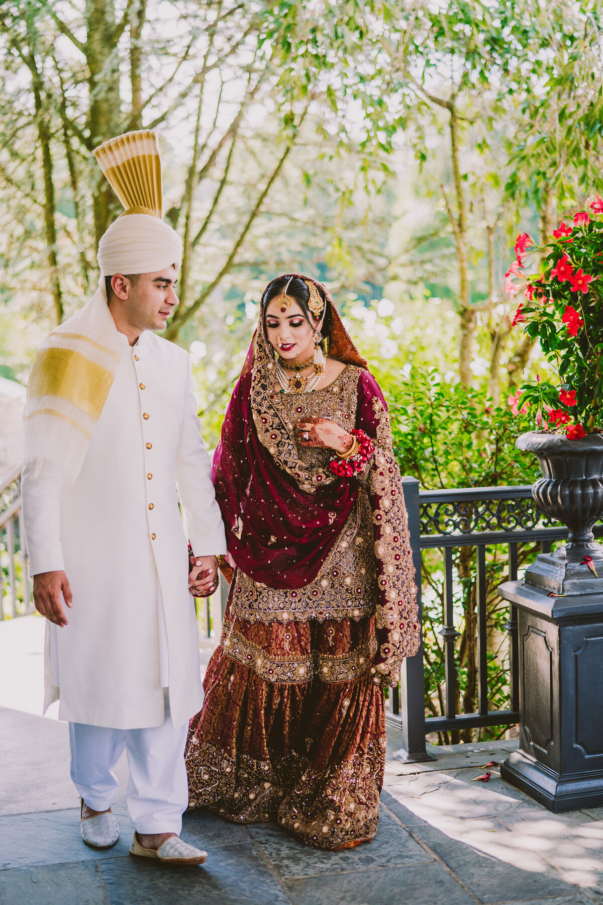 Pakistani groom wearing white and bride wearing red walking at the mansion at mountain lakes in nj after their muslim wedding nikkah ceremony