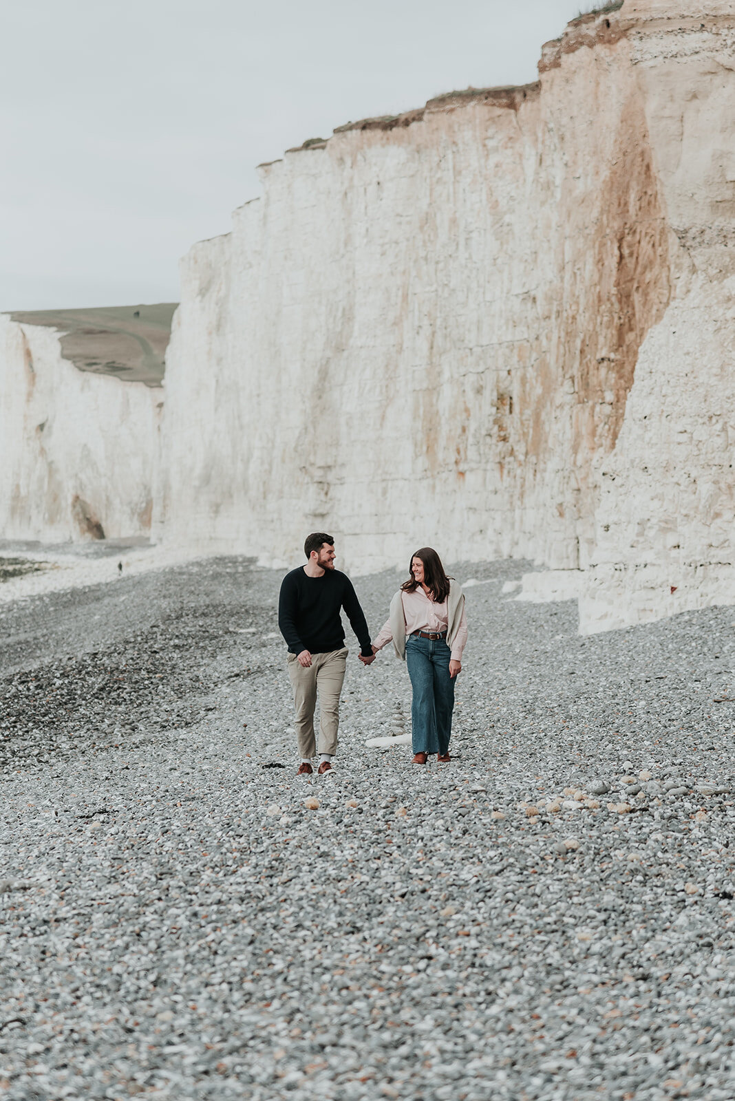 Couple walking along the white cliff beach at Birling Gap Eastbourne