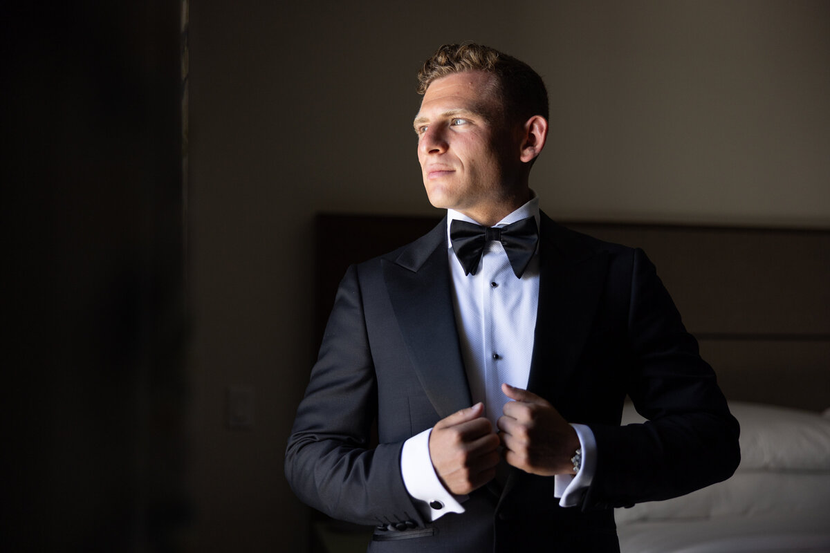 A groom holding either side of his suit jacket