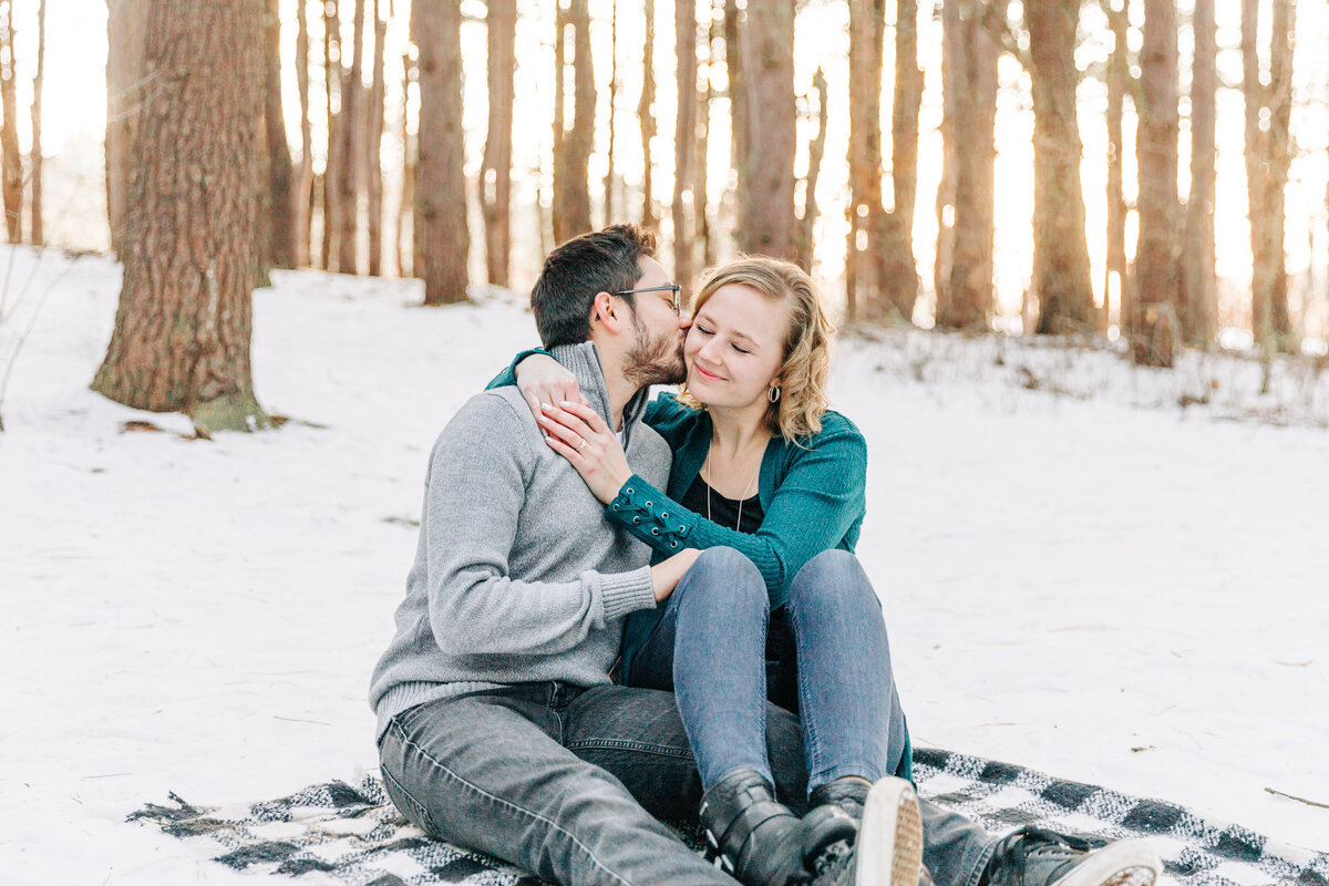 couple sitting next to each other on a blanket in the snow