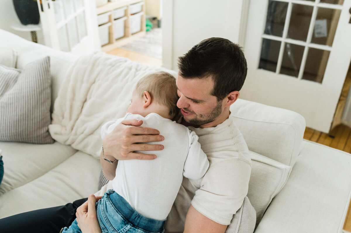 Father holding child on couch.