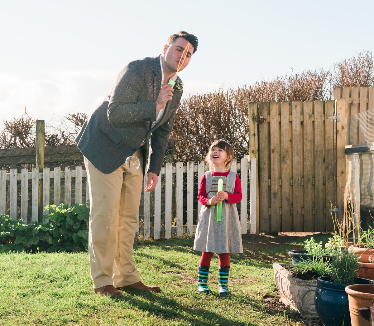 Groom blowing bubbles with child in garden