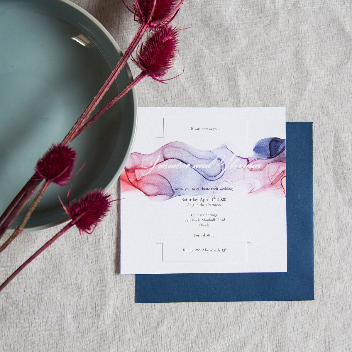 Purple blue and red wedding invitation with watercolour ink design  and a delicate font, paired with a royal blue envelope