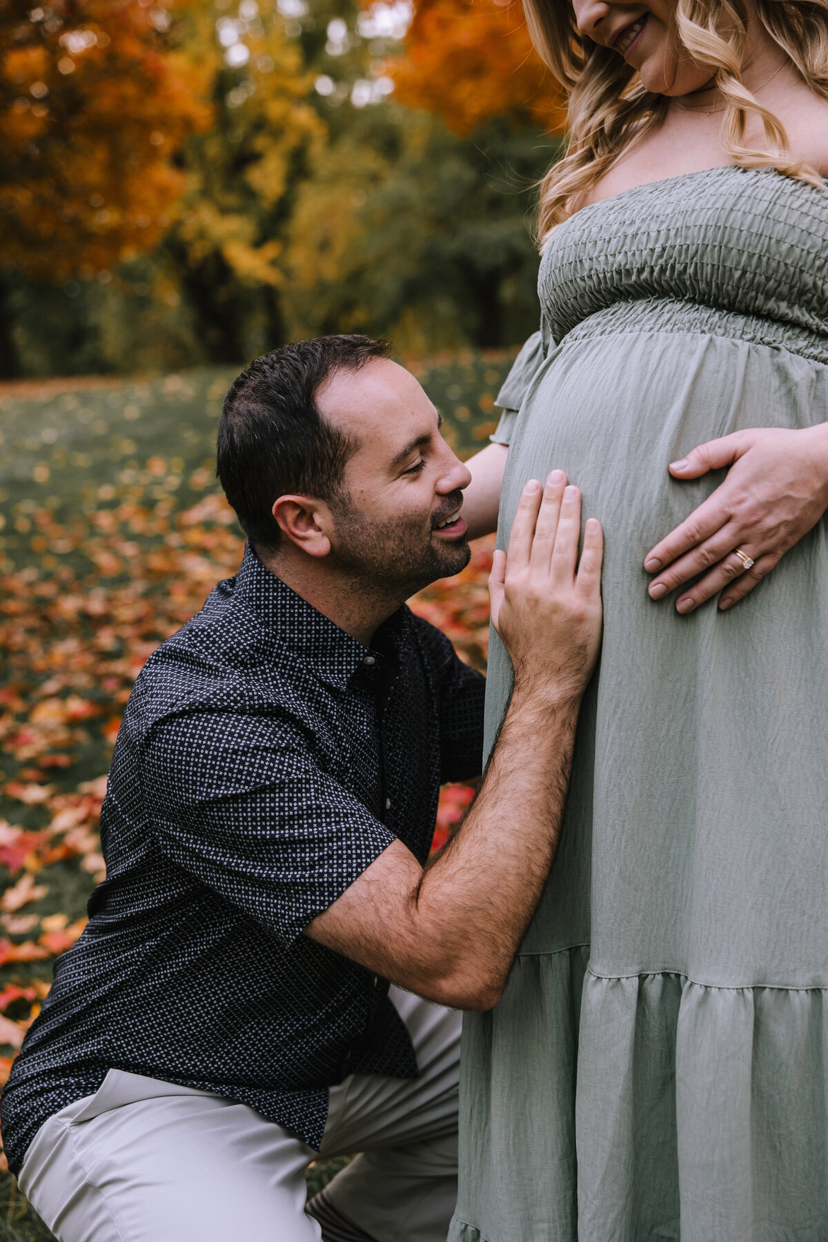 Dad kissing wife's pregnant belly in Allegheny Commons Park. 