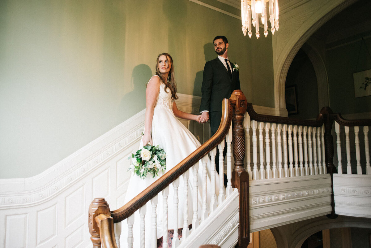 Bride and groom holding hands on the staircase