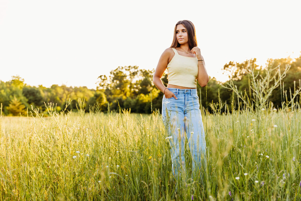 oshkosh high school student standing in a grassy field with one hand in her pocket as she looks out into the distance