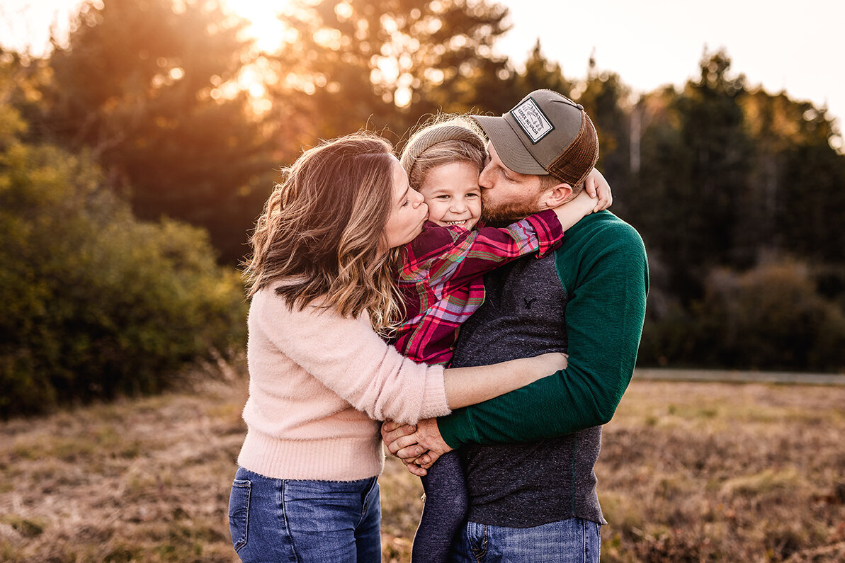 Mom and dad kissing little girl on the cheek sunset family photo session by lisa smith photography