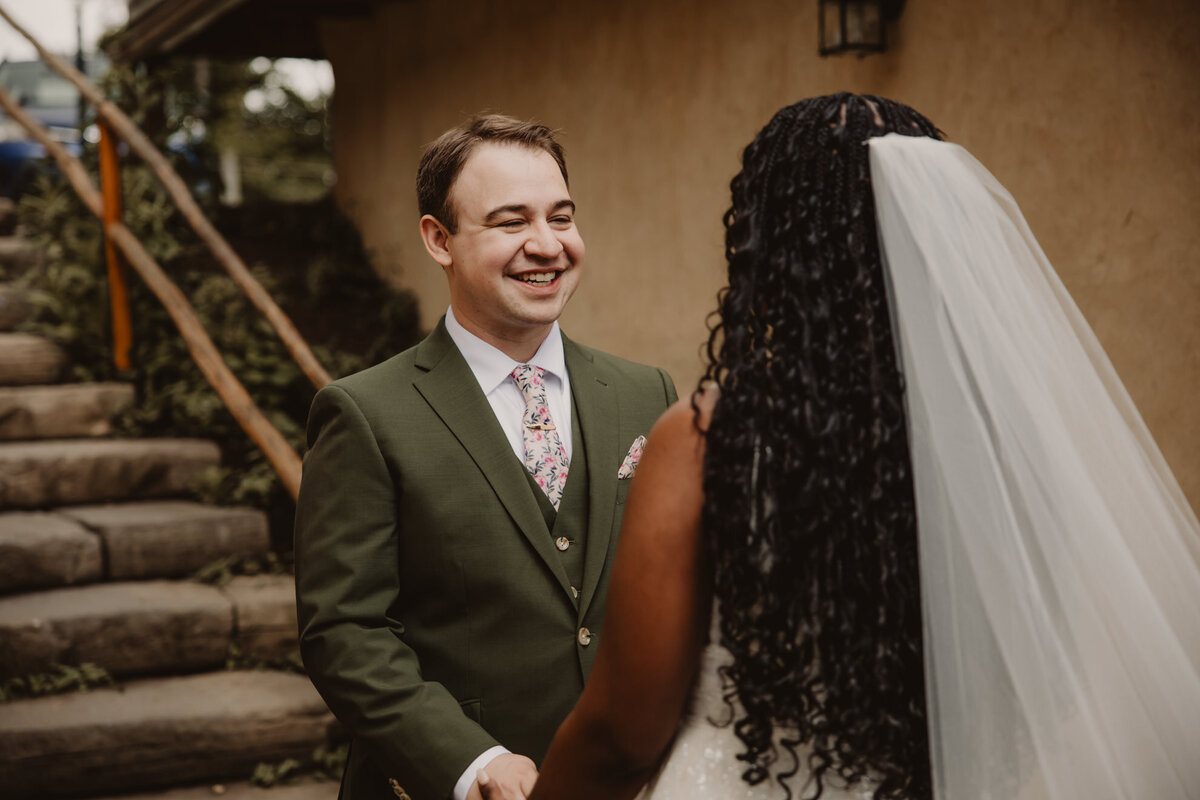 A couple holding hands and smiling during their first look 