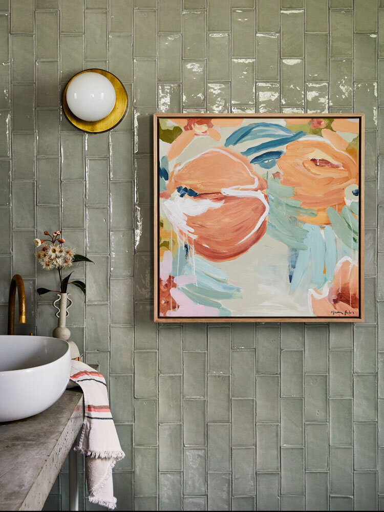 Green tiled bathroom styled by interior decorator in Melbourne, featuring artwork and soft ceramic decor.