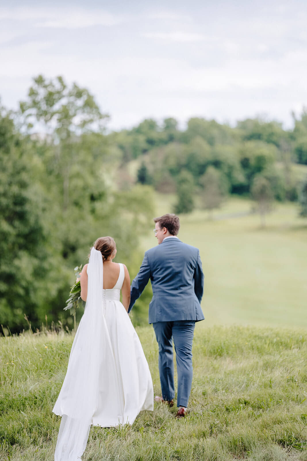 Bride and groom walking along fields at Oswego wedding, NY