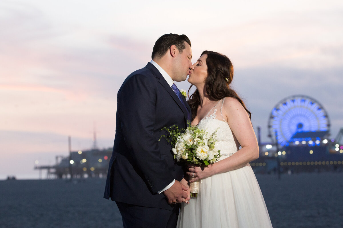 A bride and groom kissing on the beach