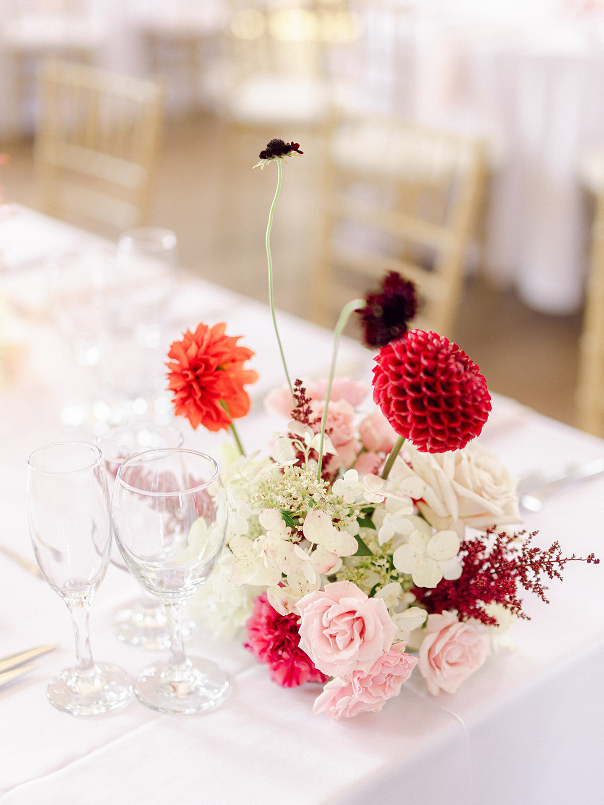 A small, lush centrepiece featuring bright red and pink flowers at a wedding reception in Montreal.