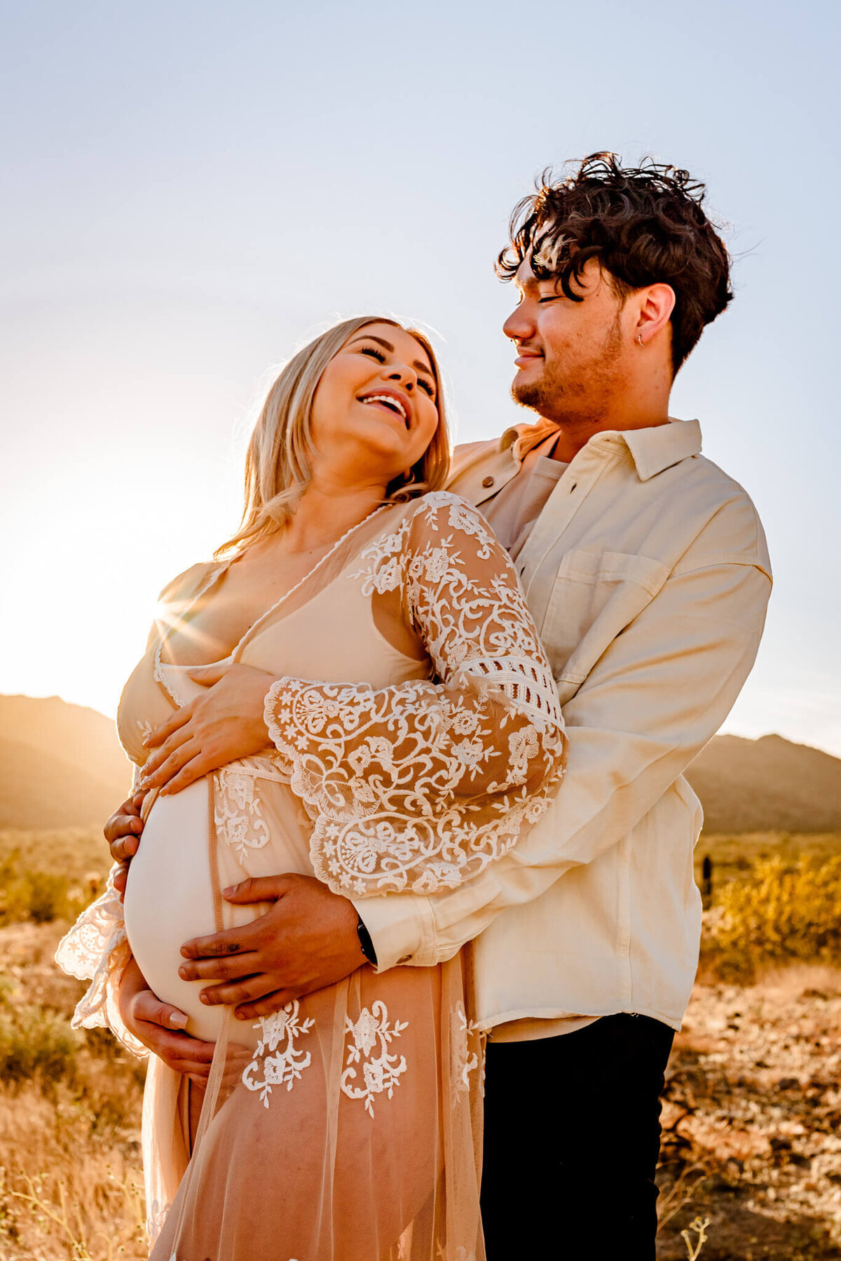 mom in boho dress laughing with husband for maternity photo session with Arizona photographer Cactus & Pine Photography LLC