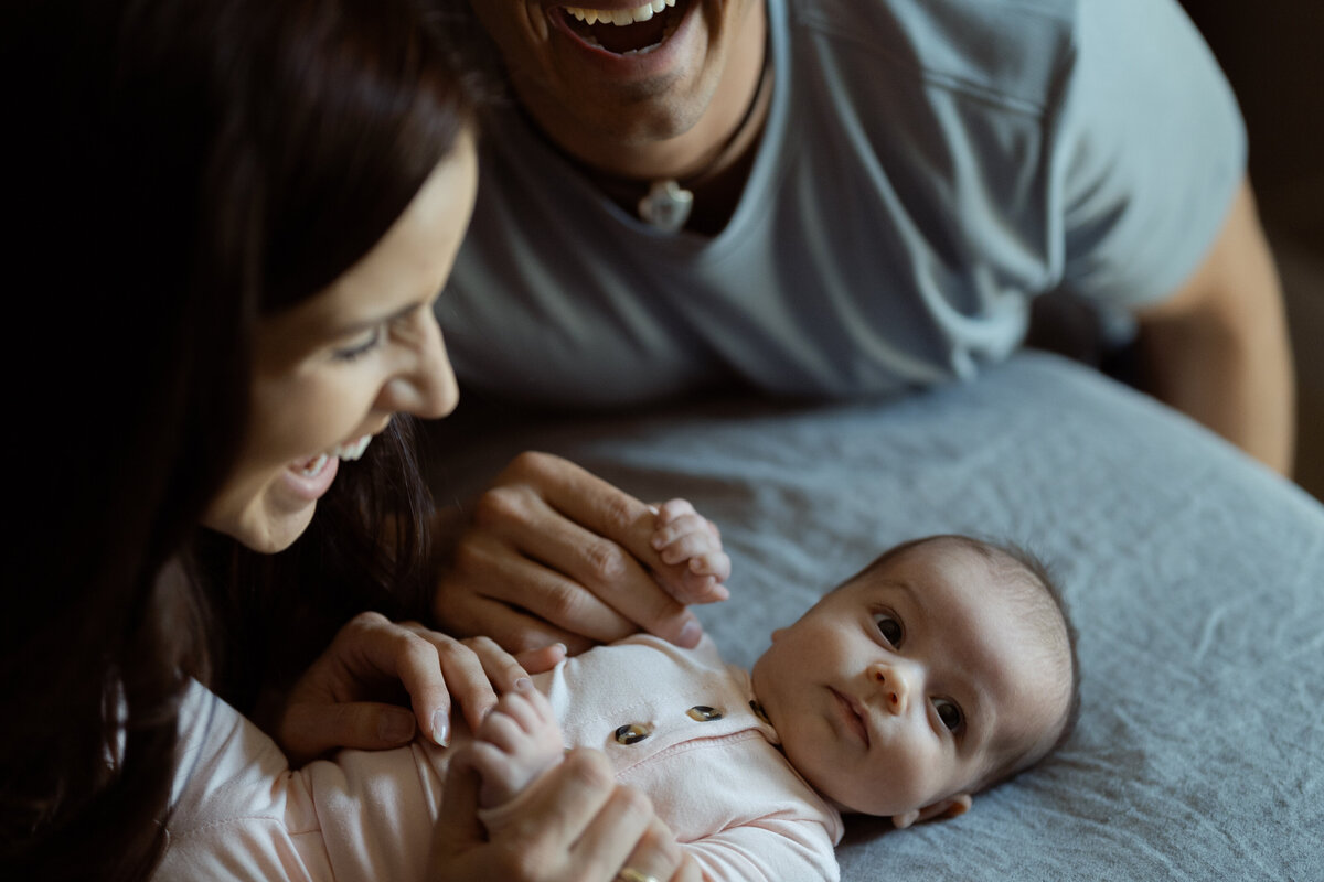 A detailed close-up of parents’ hands gently holding their baby’s tiny hand, symbolizing connection and legacy in a Fort Worth home lifestyle session.